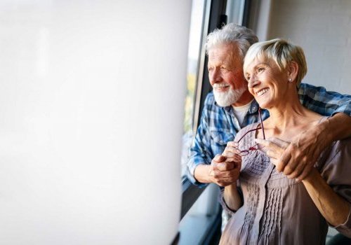 Couple mixte agé souriant regardant par la fenêtre